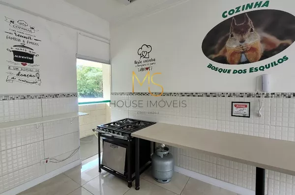 Destaque para o fogão e mesa de apoio do salão de festas