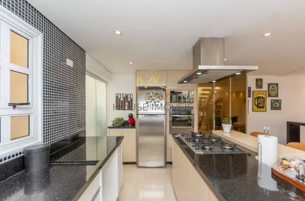 Ilha com cooktop e coifa. Ao fundo, a geladeira e a torre quente