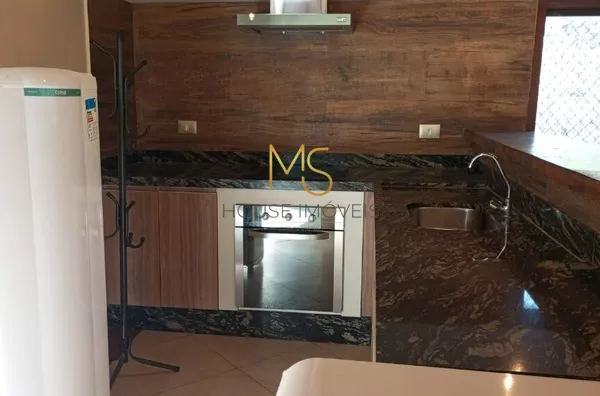 Cozinha do salão de festas com geladeira, freezer, cooktop, forno elétrico e coifa