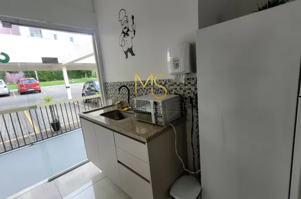 Cozinha do salão de festas equipada com pia, microondas, geladeira, fogão e mesa de apoio