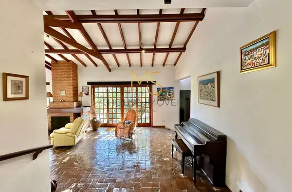 Sala com vigas aparentes, lareira e piso rústico